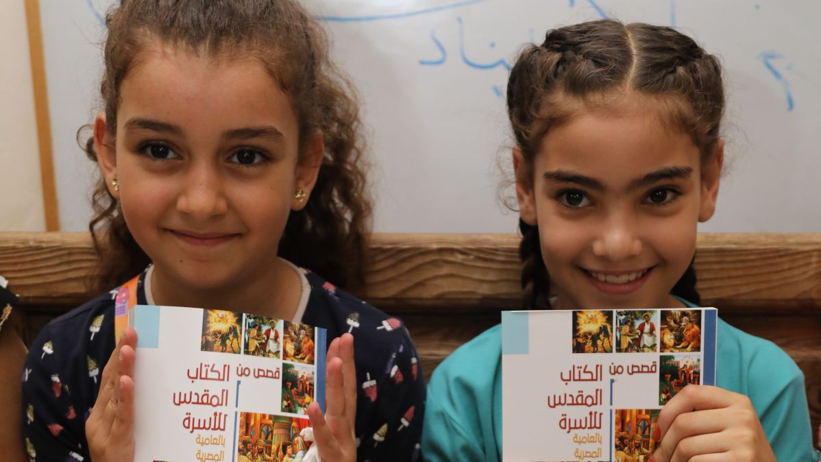 Zwei Mädchen halten freudig ihre neue Kinderbibel in die Höhe