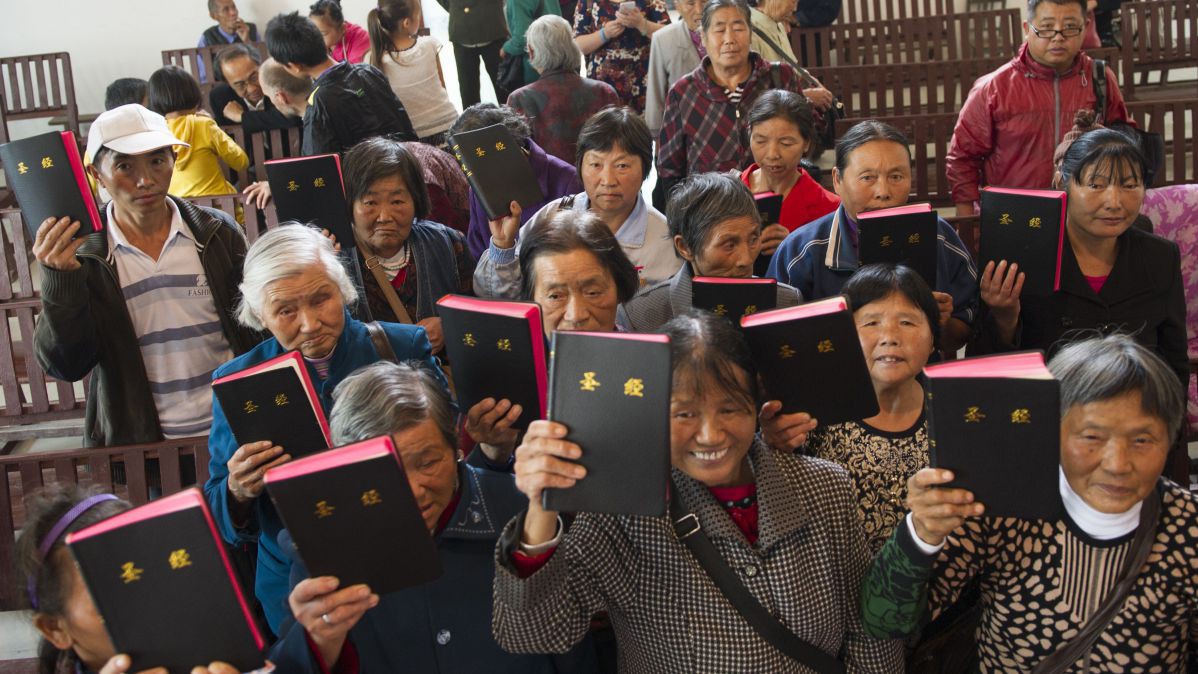 Eine Gruppe Menschen aus China, die voller Freude eine Bibel in die Höhe halten. 