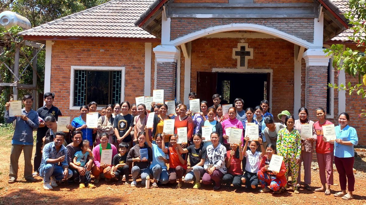 Stolz zeigen die Teilnehmenden am Lese- und Schreiblernkurs in Ou Ya Dav vor ihrer Kirche ihre Zeugnisse.