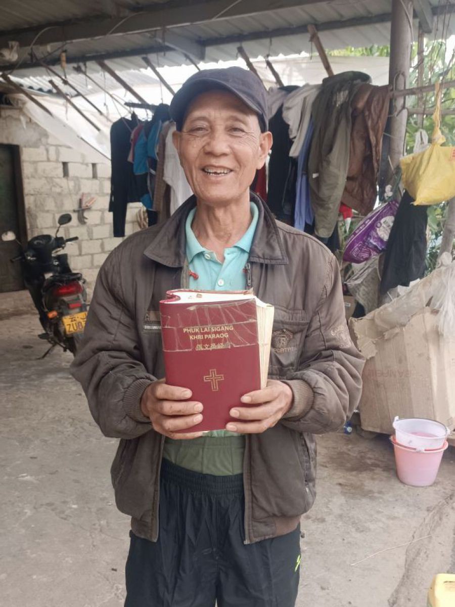 Bao Bao zeigt seine abgegriffene Bibel, die von Klebeband zusammengehalten wird, in die Kamera.