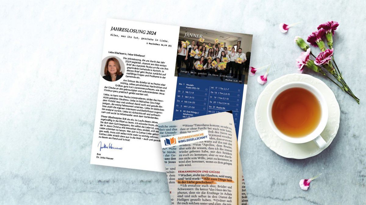 Der Bibelleseplan 2024 aufgeschlagen neben einer Tasse Tee