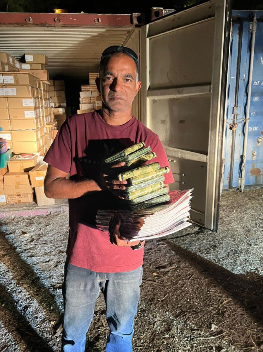 Ein Mann mit mehreren Bibeln in der Hand steht vor einem offenen Frachtcontainer