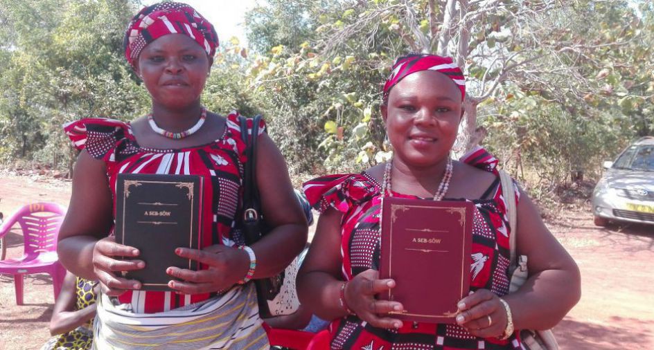 Zwei Frauen in traditioneller Kleidung halten die neue Bibelübersetzung in Dagaare, einer westafrikanischen Sprache, in Händen.
