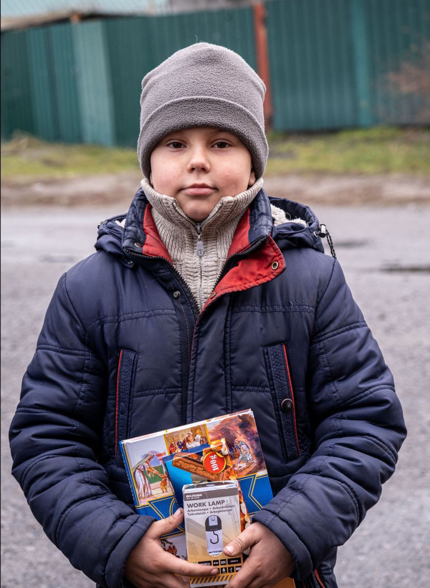 Ein Junge hält eine ukrainische Kinderbibel und ein batteriebetriebenes Licht in der Hand.