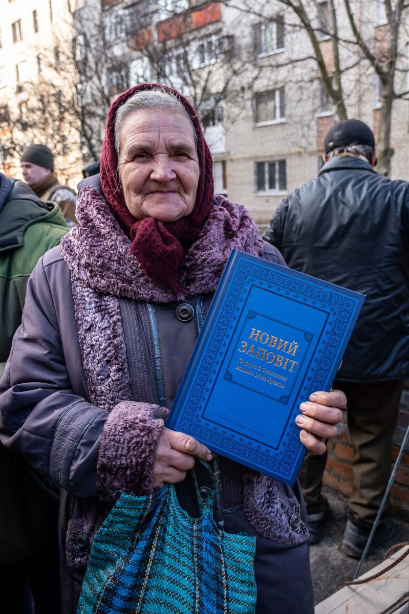 Eine ältere Dame zeigt stolz ihre neue Ukrainische Bibel herzeigt