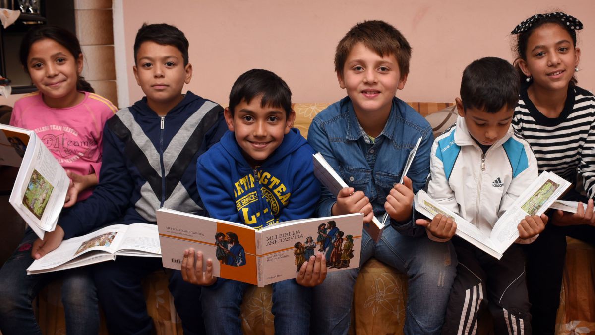 In den Kursen der Bibelgesellschaft lernen diese Roma-Kinder, ihre Muttersprache Romanes zu lesen und zu schreiben. Sie genießen die Zuwendung der Mitarbeitenden und schließen neue Freundschaften. Gruppe junger Schülerinnen mit Kinderbibel in Romanes