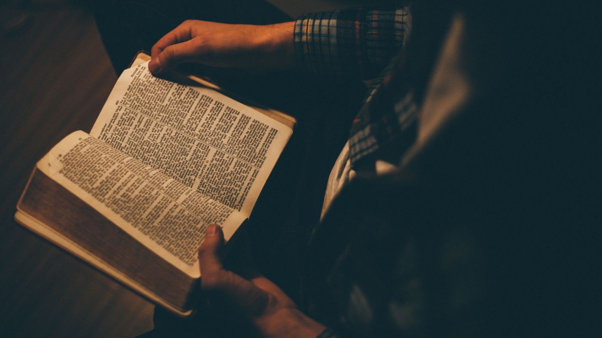 Person mit aufgeschlagener Bibel in Händen-