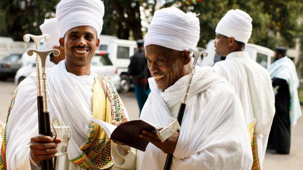 Zwei äthiopische Christen in traditioneller Kleidung mit dem veröffentlichten Neuen Testament auf Ge'ez.