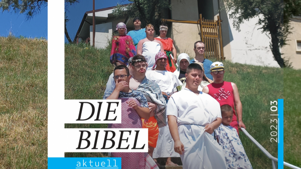 Das aktuelle Cover des Magazins "die Bibel Aktuell" eingebettet in das Foto aus dem das Coverbild geschnitten wurde. Man sieht eine Schar junger Menschen mit Down-Syndrom verkleidet als Figuren aus biblischer Zeit.