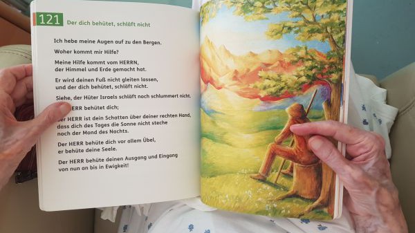 Aufgeschlagenes Psalmenbuch der Österreichischen Bibelgesellschaft in den Händen einer älteren Person.