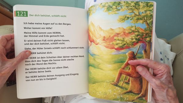 Aufgeschlagenes Psalmenbuch der Österreichischen Bibelgesellschaft in den Händen einer älteren Person.