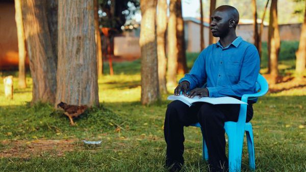 Patrick Owiyo liest in einem Band der Braille-Bibel in Acholi. Für diese Braille-Bibel in seiner Sprache hat er gekämpft - und jetzt bereitet er sich darauf vor, Pfarrer zu werden. 
