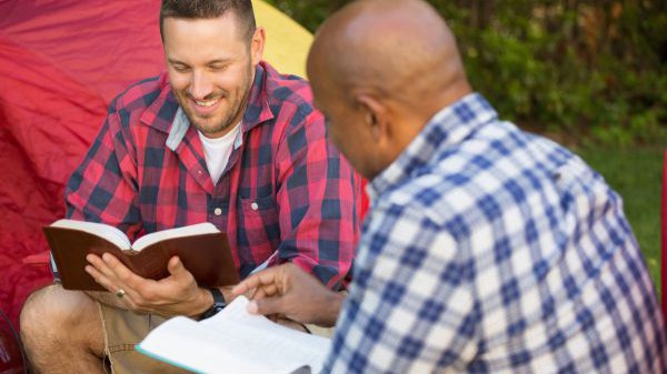 Zwei Männer in karierten Hemden lesen in ihrer Bibel und unterhalten sich darüber.